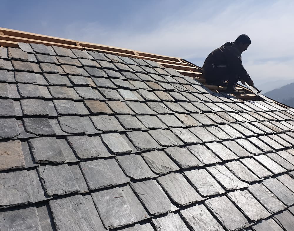 Roofer laying natural slate tiles