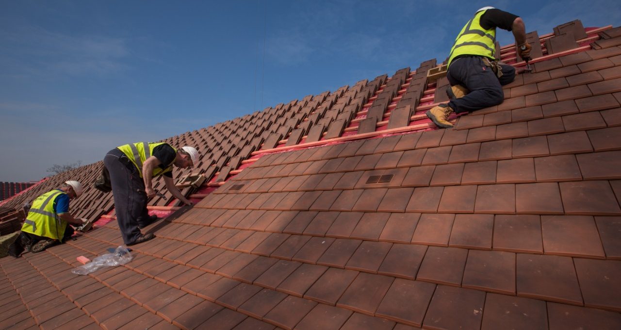 Roofer fixing tiles on a UK roof
